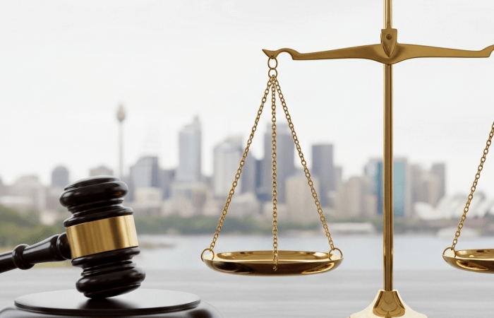 Scales of justice and a gavel with a blurred Sydney skyline in the background, representing civil and criminal appeals in New South Wales.