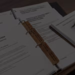 A professional top-down, close-up landscape header image featuring a subtle dark color overlay for website hero text compatibility. The desk workspace displays organized legal files and binders from Citilawyers, including a "Dispute Case Strategy Brief | Assessing Breach of Contract Claims" document with specialized leather index tabs labeled "Relevant Terms," "Breach of Supply / Business Sale / Warranty Claims," "Restraint / Confidentiality," and "Debt Recovery / Non-Payment." On the right, a commercial litigator's hand in a professional suit holds a classic fountain pen, drafting notes on a notepad with the heading "Uniform Civil Procedure Rules" next to an open "Deed of Variation" document.